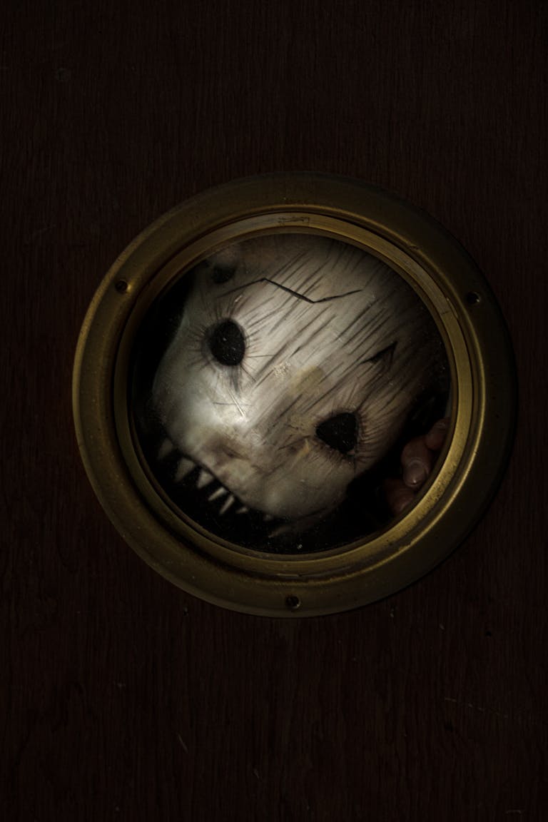 A scary masked face peering through a porthole window creates a haunting atmosphere.